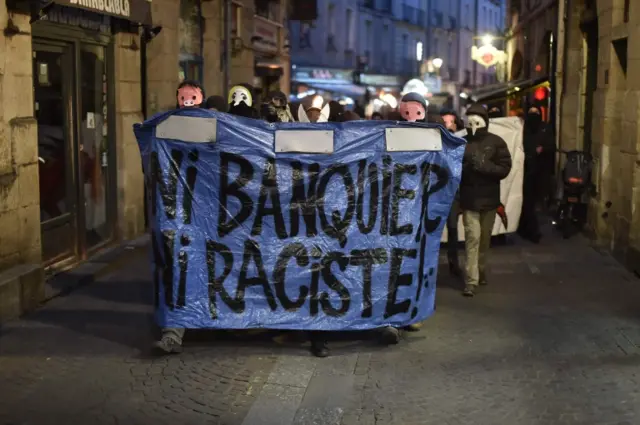 Left-wing demonstrators march in Nantes, western France, waving banners that translate as "not a banker nor a racist", 23 April 2017