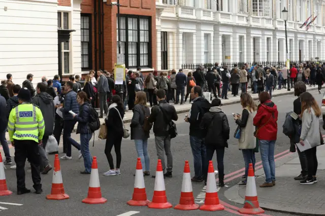 a long and winding queue in the street outside the Lycee Francais Charles de Gaulle