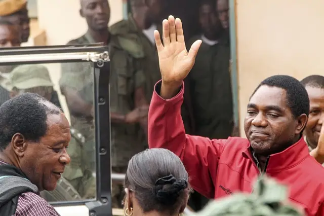 Zambian opposition leader Hakainde Hichilema waves to supporters from a police van as he leaves a courtroom in Lusaka on April 18, 2017.