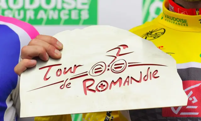 A cyclist holding a logo of the Tour de Romandie