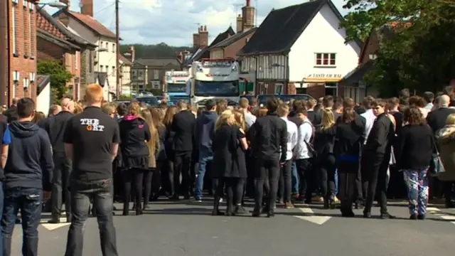 Crowds in Harleston, with the convoy of lorries in the background