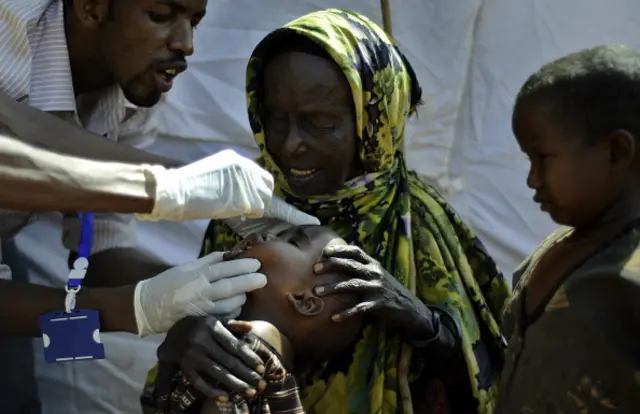 Howa Hassan (C), a blind Somali octogenarian refugee, sits with her grandchildren as one of them is vaccinated at a paediatric vaccination centre at Hagadere refugee site within the Dadaab refugee complex in Kenya's north-east province on August 1, 2011.