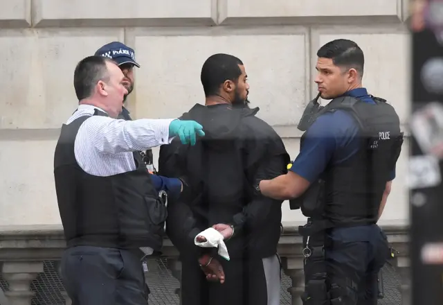 A man being held under arrest by officers