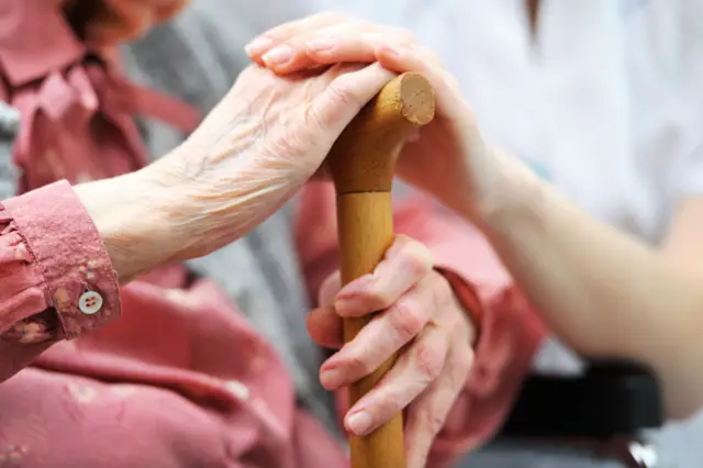 Carer holding hands with care home resident