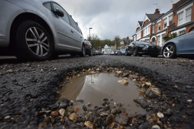A pothole in the road, with vehicles