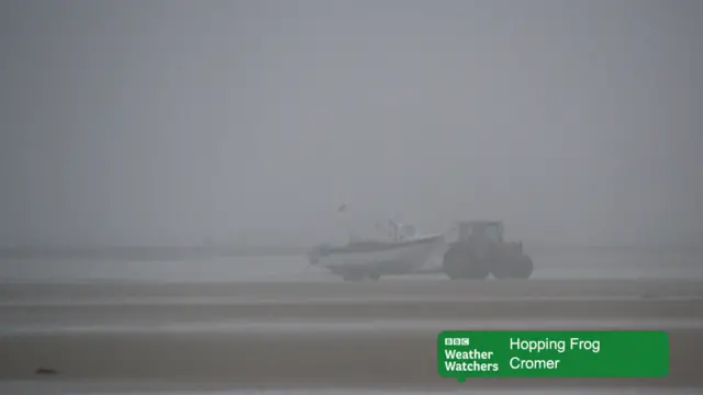 Fishing boat and tractor on the sands, in mist, at Cromer