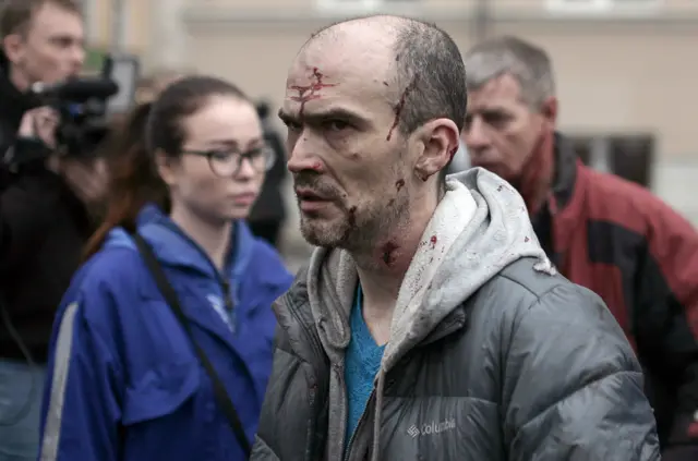 
          An injured man is helped by medics outside Tekhnologichesky Institut metro station in St Petersburg
        