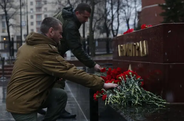 
          Men lay flowers during a memorial service for victims of a blast in St Petersburg metro, at a memorial by the Kremlin walls in Moscow, Russia
        