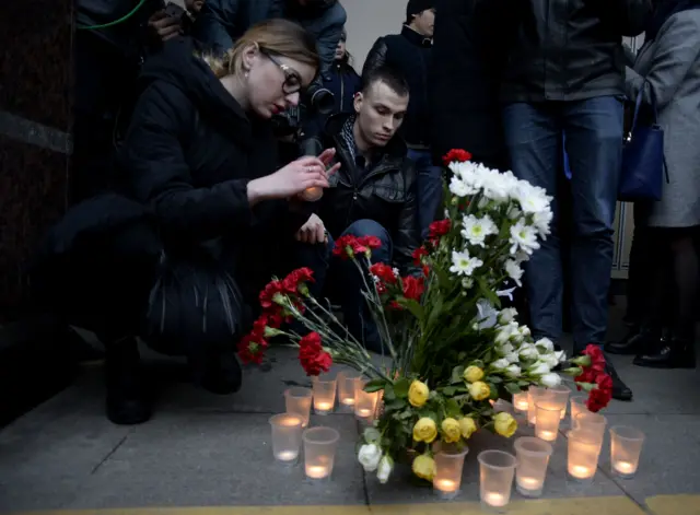 
          People place flowers and lit candles in memory of victims of the blast in the Saint Petersburg metro outside Sennaya Square station
        