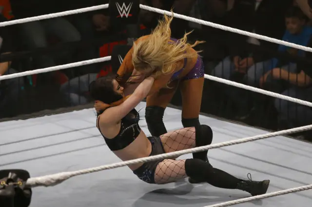 Paige, in black, challenges Charlotte, in the ring