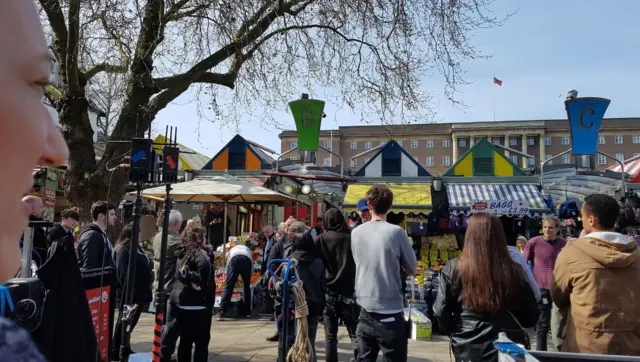 Film crew by the market place, with City Hall in background