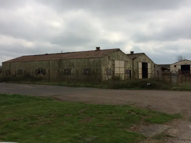 Two long buildings, with red roofs, one with open door