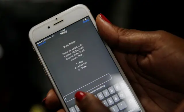 A delegate uses her cell phone to buy a M-Akiba bond