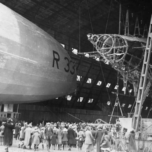 
          April 1925: A landing party follow the airship R33 into its hangar at Pulham, Norfolk
        