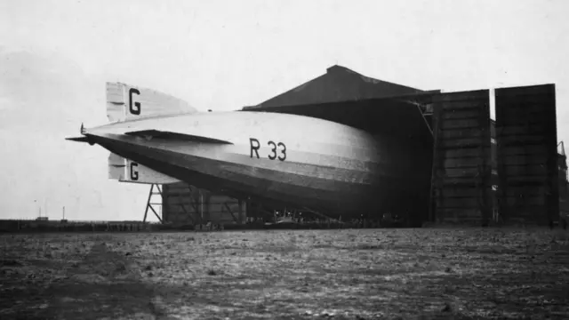 
          April 1925: The R33 airship emerges from its hangar to begin a series of trial flights for research purposes
        