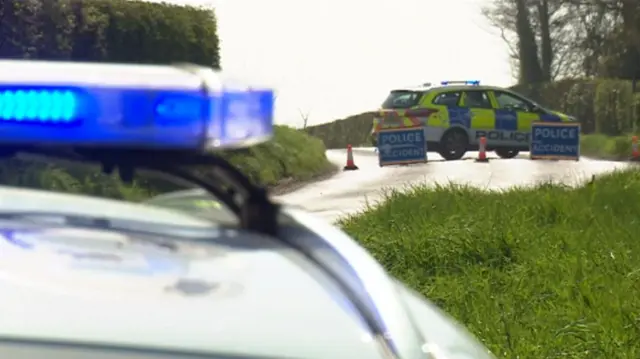 
          Police vehicle with blue light and a second police vehicle in background
        