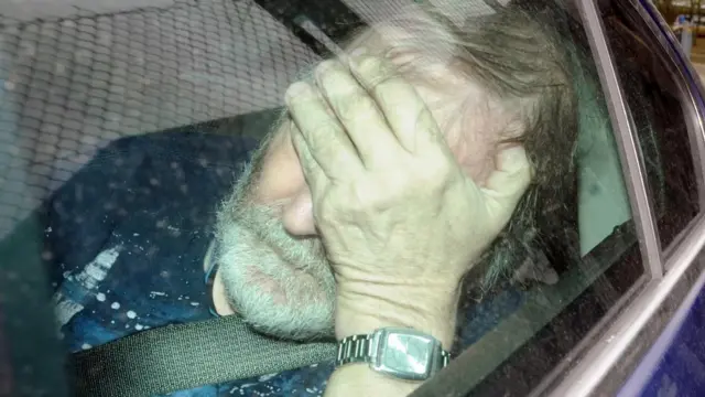 Keith Baker in vehicle, with hand over eyes