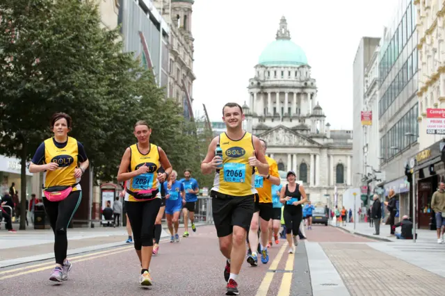 Runners in the Belfast Marathon, with City Hall in the background