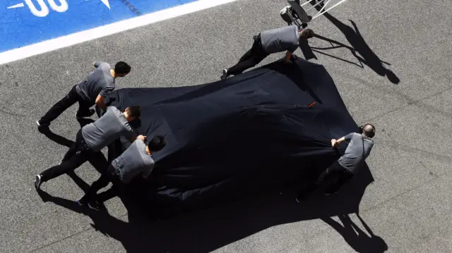 Fernando Alonso's McLaren is pushed back to the garage