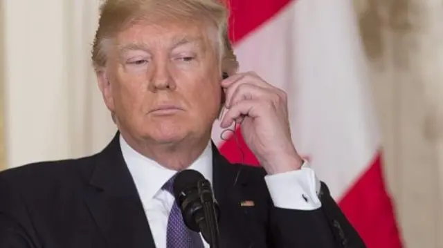 US President Donald Trump listens to an earpiece during a joint press conference with Canadian Prime Minister Justin Trudeau