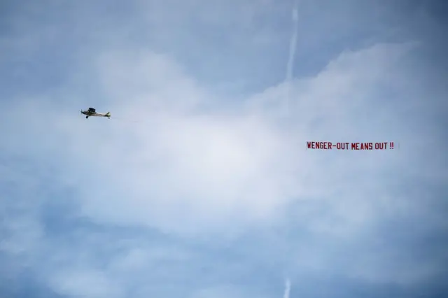 A plane flies over reading 'Wenger out'