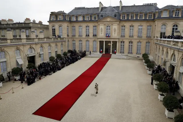 An employee prepares the courtyard near the red carpet at the Elysee Palace as journalists (L) wait for French President-elect Emmanuel Macron to arrive for the handover ceremony with outgoing President Francois Hollande in Paris, France, May 14, 2017