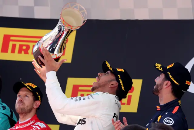 Lewis Hamilton celebrates with his trophy