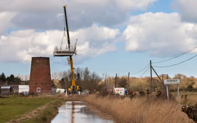 A view of the crane lifting the cap from the windpump