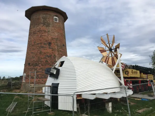 Windpump, with new cap lying on the ground by brick tower