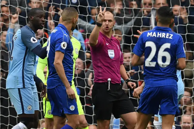 Referee Robert Madley talking to Riyad Mahrez