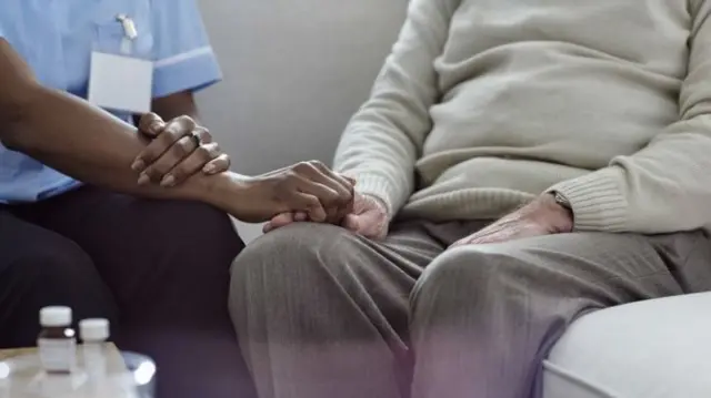 Nurse holding older person's hand