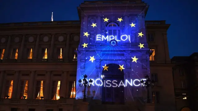 The words Employment and Growth (in French) and the logo of the European Union  are projected during a light show on to the French foreign ministry building in Paris