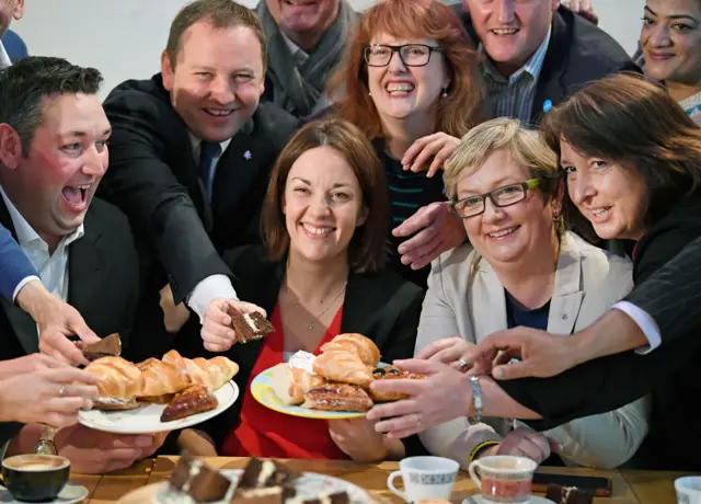 People reaching for a plate of cakes