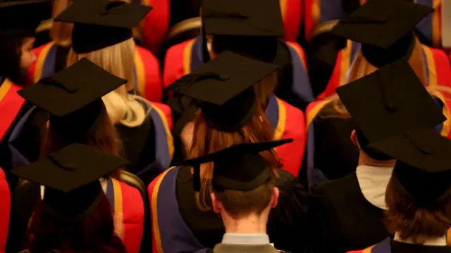 students at graduation ceremony in caps and gowns