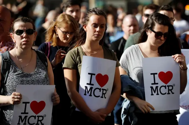 people hold signs at Manchester vigil