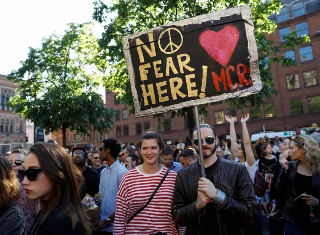 people hold signs at vigil