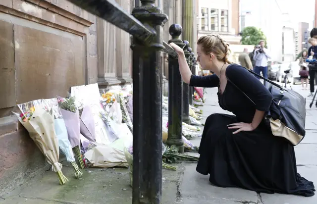 Woman lays flowers at St Ann's Church Manchester