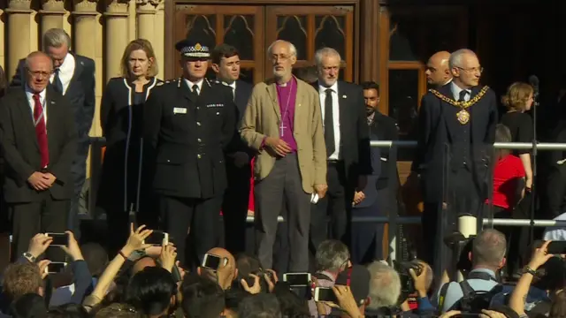 politicians stand on stage at vigil