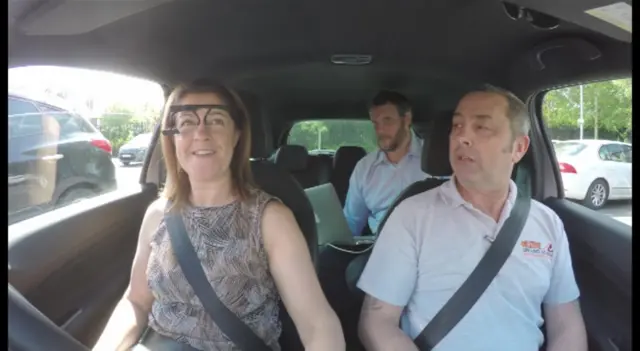 People in car with woman wearing eye tracking device