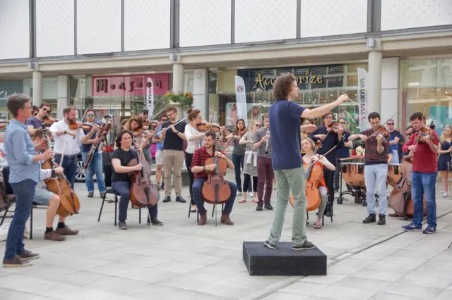 Man conducting orchestra in Chequer Square