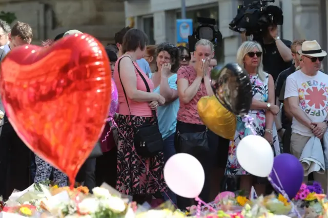 People look at tributes in St Ann's Square, Manchester, before a minute's silence to remember the victims