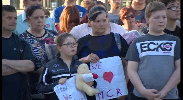 People holding up signs and teddy bears