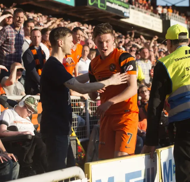 A fan helps United midfielder Blair Spittal after he falls into the stand