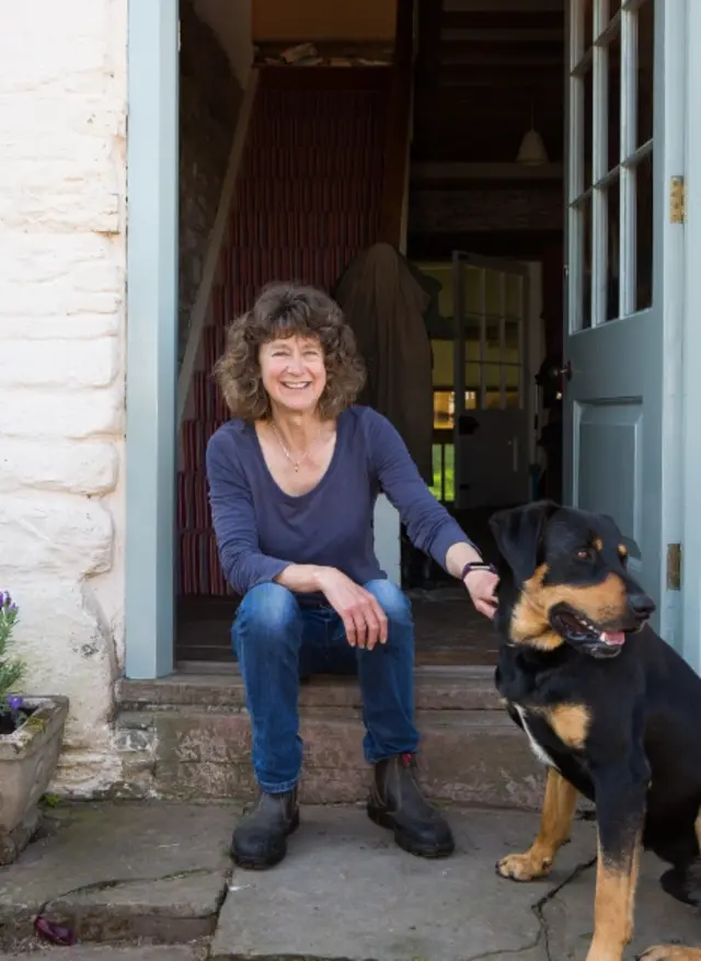 Penny Chantler and her dog sit on her doorstep at Hill Farm, Llanigon