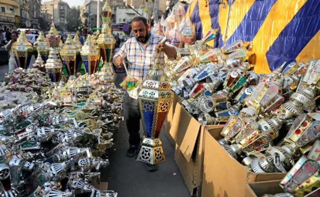 An Egyptian seller dusts a traditional Ramadan lantern called "fanous" at his shop stall ahead of the Muslim holy month of Ramadan