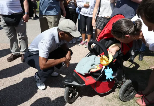 Barack Obama greets a baby while playing golf in St Andrews