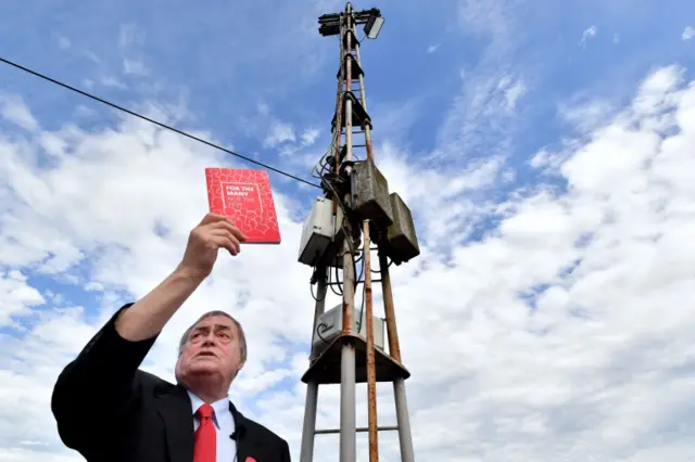 Lord John Prescott holds a copy of the Labour party manifesto during a stump speech at Ashton United Football Club