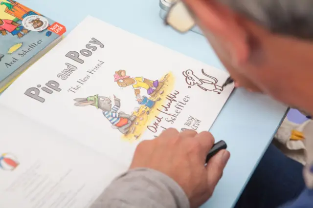 Axel Scheffler draws a mouse in a fan's book at the Hay Festival