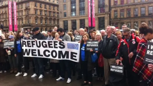 People with refugees are welcome signs