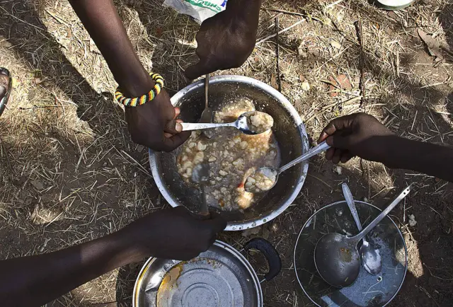 People eating from a cooking pot